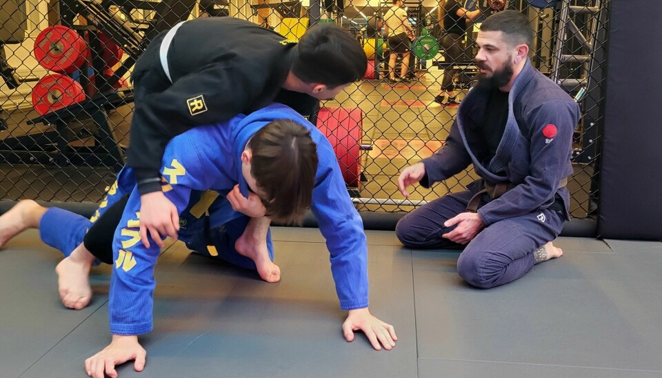 Espen Kihlman instruerar två ungdomar på mattan i brasiliansk jiu jitsu.