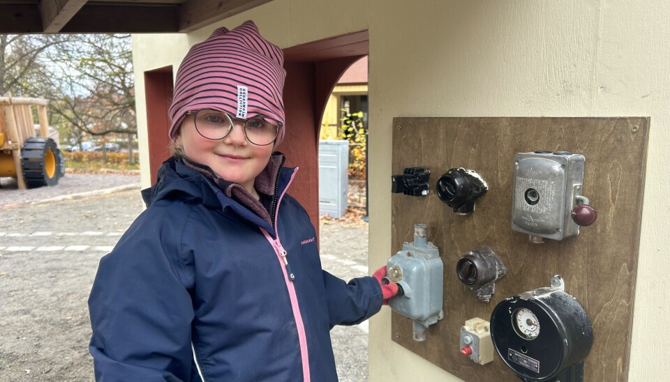 Hilda, 5 år, knappar och rattar inne i järnvägsstationsbyggnaden.