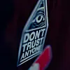 Närbild på klistermärke med ett öga och texten 'DON'T TRUST ANYONE' mot mörk bakgrund.